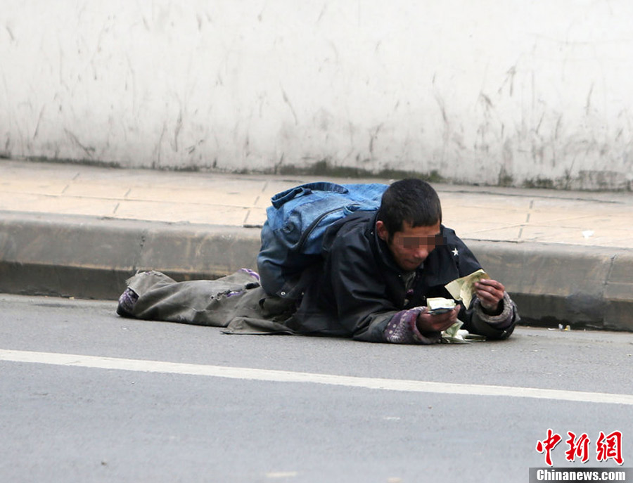 成都街头一男子趴地装"瘫"行乞