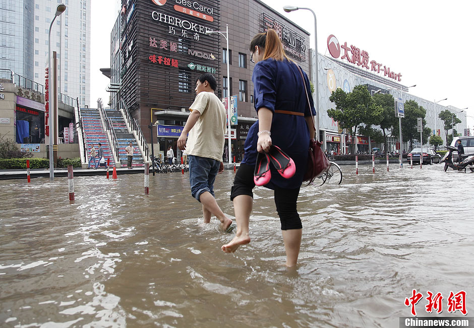 上海暴雨致地铁口积水 市民涉水前行