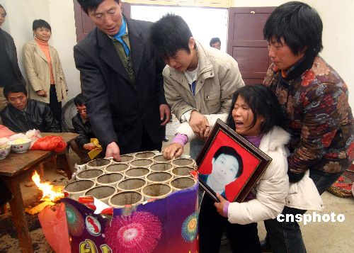 杨建文的妻子悲痛不已地拍打使她丈夫遇难花炮.