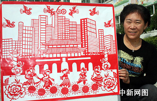河南周口,陈雪英老师在展示她为喜迎建国60周年而创作的剪纸作品